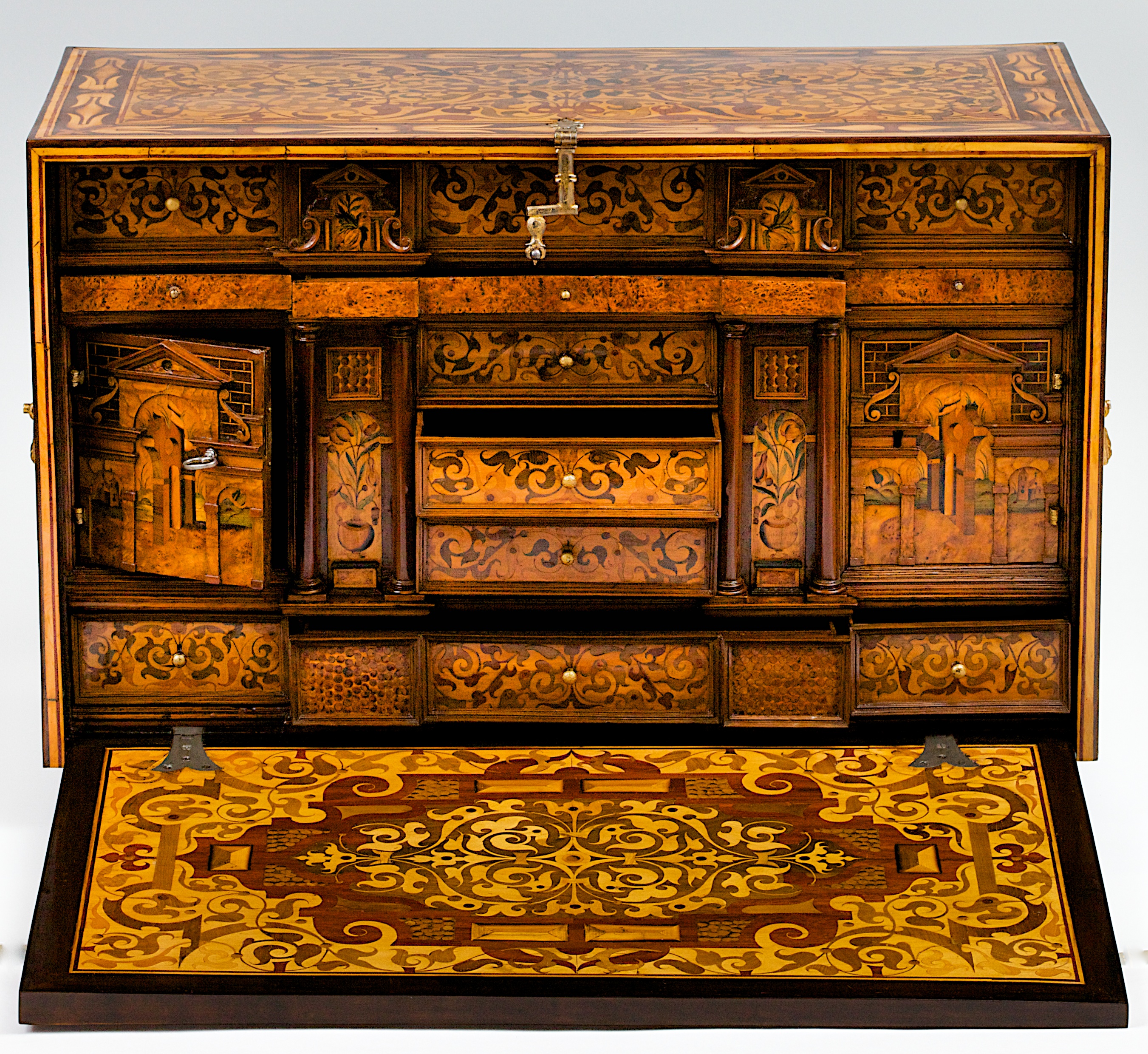 Augsburger Schreibkabinett. Auf vier gedrechselten Beinen stehender rechteckiger Kasten mit Seitengriffen und Fallschloss. Der Korpus reichlich dekoriert mit Pflanzenmarketerien. Die Ruinenintarsien auf den beiden Innentürchen sind typisch für Augsburger Schränke aus der 2. Hälfte des 16. Jahrhunderts.<br><br>geflammtes Nussbaumholz, gravierte und gefärbte Obsthölzer, auf Eiche und Weichholz furniert, vergoldete Beschläge | Ralph Gierhards Antiques & Fine